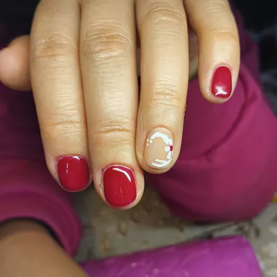 Esmaltado rojo con una uña decorada en blanco