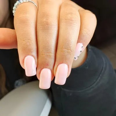 Softgel rosa pastel cuadrado con pedrería en una uña